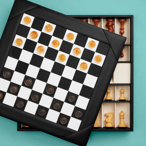 Luxury leather chessboard and checker set, shown with chess pieces on board. Black leather, opened to see storage space for pieces. Set with checkers on board.