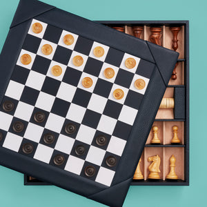 Luxury leather chessboard and checker set, shown with chess pieces on board. Navy leather, opened to see storage space for pieces. Set with checkers on board.