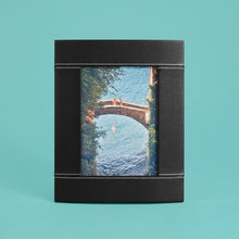 Load image into Gallery viewer, High-end leather picture frame with white contrast stitching. Holds 5x7&quot; photo. Black leather shown, standing vertically.
