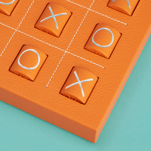 Luxury leather tic tac toe board with white stitching. Shown in orange leather. Close-up of corner shown to highlight high-quality leather and stitching detail.